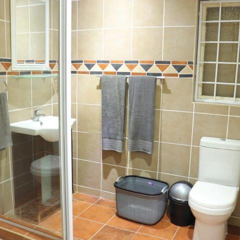 Bathroom with shower, sink, toilet, towels, and laundry basket.