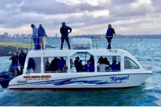 White boat with people in navy attire on a scenic waterway.