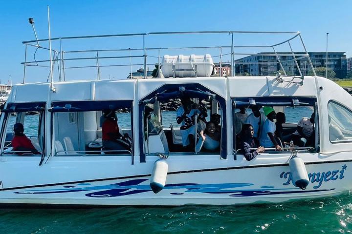 People on a white boat with blue accents in a marina.